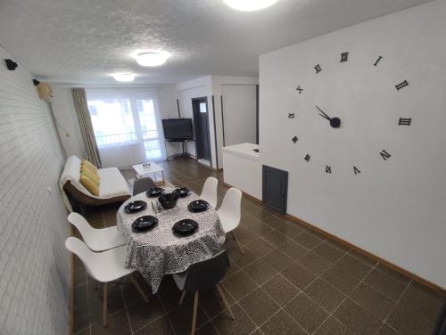 - un salon avec une table et une horloge murale dans l'établissement Апартамент Фамилия 100м от морето в Равда, à Ravda