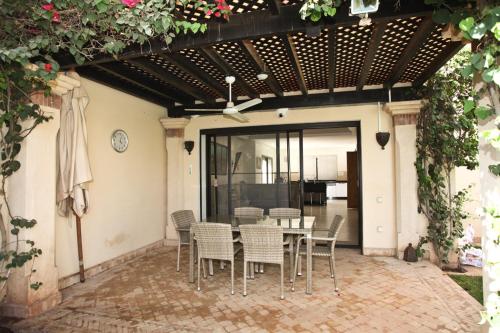 un patio con mesa y sillas bajo una pérgola en Exceptionnelle Villa duplex 3 ch avec piscine privée dans résidence fermée, en Riaïna