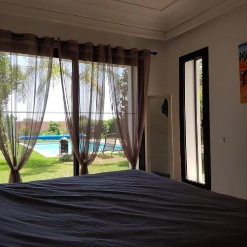 a bedroom with a bed and a large window at Exceptionnelle Villa duplex 3 ch avec piscine privée dans résidence fermée in Riaïna