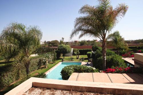 una piscina en un patio con palmeras y flores en Exceptionnelle Villa duplex 3 ch avec piscine privée dans résidence fermée, en Riaïna