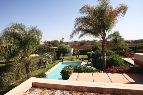 a swimming pool in a yard with palm trees and flowers at Exceptionnelle Villa duplex 3 ch avec piscine privée dans résidence fermée in Riaïna