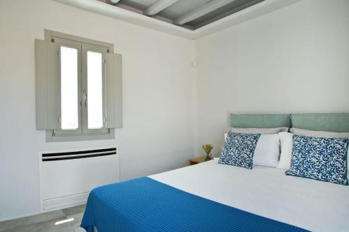 DexamenesにあるBoutique Mykonos Villa - Heated Hot-Tub - Wonderful views - Villa Heart - Agia Sofiaの白いベッドルーム(青と白の枕が付くベッド付)