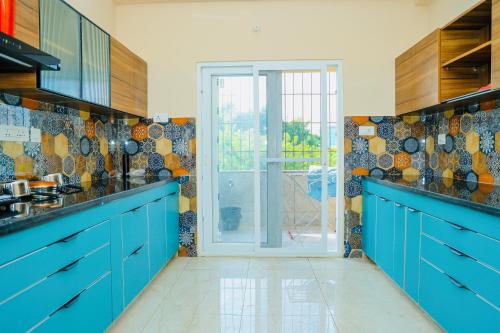 a blue kitchen with blue cabinets and a glass door at Swayamkrushi 4th floor in Hyderabad