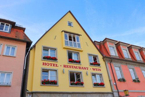 un edificio amarillo con flores en las ventanas en Laurentius Boutique-Hotel & Restaurant, en Weikersheim