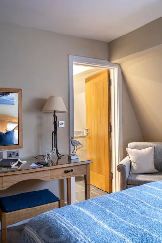 a bedroom with a desk and a bed and a mirror at South Sands Hotel in Salcombe