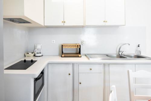 a white kitchen with white cabinets and a sink at Elysium in Glinádhon