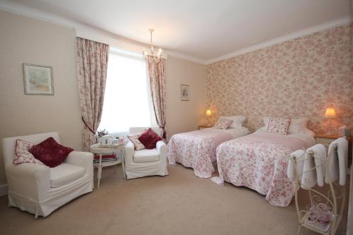 a bedroom with two beds and chairs and a window at The Old House in Nether Stowey