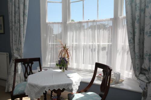 a dining room table with two chairs and a window at The Old House in Nether Stowey