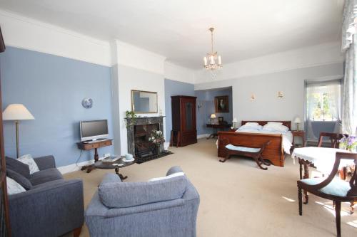 a living room with a bed and a couch and chairs at The Old House in Nether Stowey