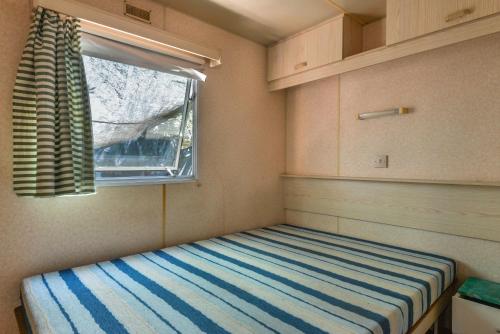 a small room with a bed with a window at Casetta Mobile al mare di Cavo in Cavo