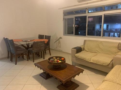 uma sala de estar com um sofá e uma mesa em Apartamento Astúrias a menos de 50m da praia no Guarujá