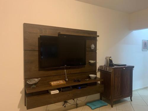 een entertainmentcentrum met een flatscreen-tv aan de muur bij Apartamento Astúrias a menos de 50m da praia in Guarujá