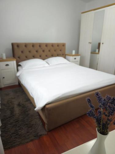 a bedroom with a large bed and a vase of flowers at Iosia Premium Apartment in Oradea