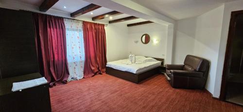 een kamer met een bed, een stoel en een raam bij Hotel Bran Stoker in Bran