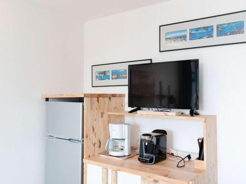 Elle comprend une télévision à écran plat installée au-dessus d'une étagère en bois. dans l'établissement Appartement T2 bord de mer 2 pers, animaux admis, parking public, location draps & serviettes - FR-1-409-25, à Narbonne-Plage