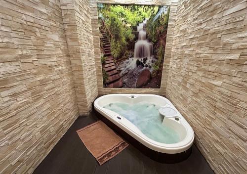 a bathroom with a bath tub with a picture of a waterfall at Ostrzycka Gościna u Maryli in Ostrzyce