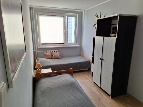 um pequeno quarto com 2 camas e uma janela em krynicka em Breslávia