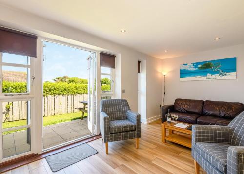 a living room with a couch and chairs and a balcony at Bay Retreat Villas in St Merryn