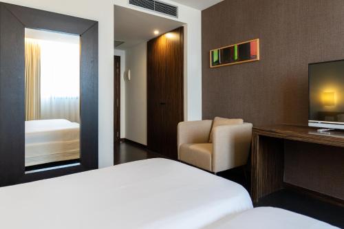 a hotel room with a bed and a chair and a television at ETH Rioja in Haro