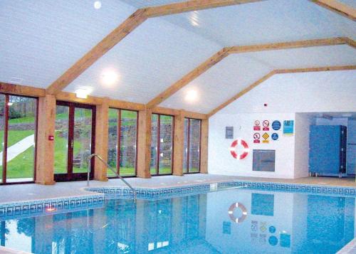 a large swimming pool in a building with windows at Green Acres Cottages in Par
