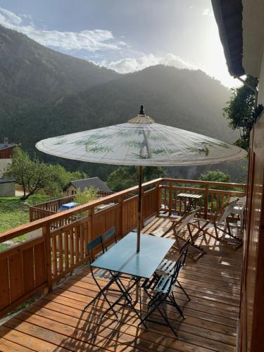 une table et des chaises sur une terrasse avec un parasol dans l'établissement Le Sarana : 75m2, calme, belle vue avec terrasse., à Les Deux Alpes