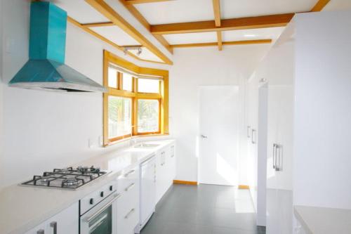 uma cozinha com balcões brancos e um forno com placa de fogão em Knights rd beauty em Lower Hutt
