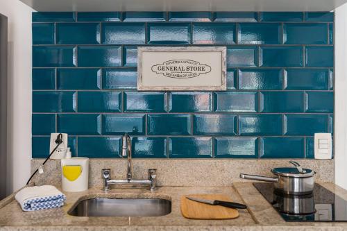 a kitchen sink with a blue tile back splash at CPM- Praça MADÁ By Anora Spaces in Sao Paulo