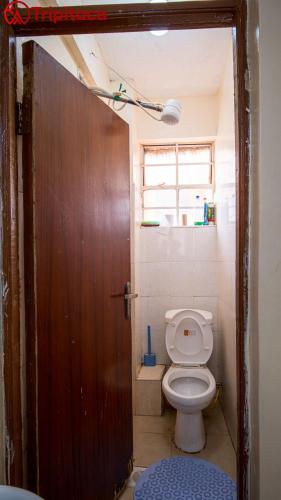 ein Badezimmer mit Toilette und Holztür in der Unterkunft Cutie homes in Nairobi