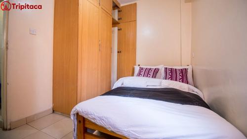 ein kleines Schlafzimmer mit einem Bett mit weißer Bettwäsche und rosa Kissen in der Unterkunft Cutie homes in Nairobi