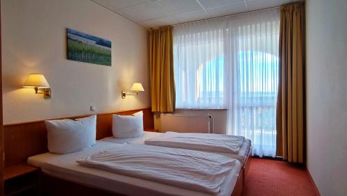 フライブルクにあるHotel Rebschuleのベッドと大きな窓が備わるホテルルームです。
