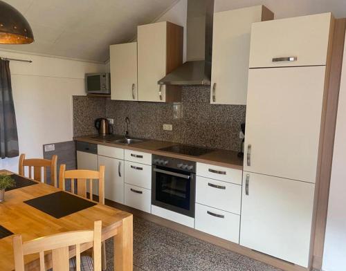 a kitchen with white cabinets and a wooden table at Ferienwohnung Rosl in Waldkirchen