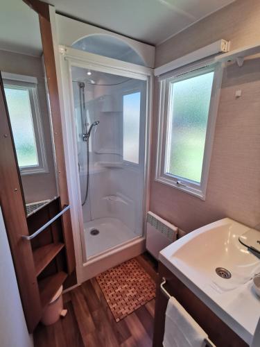 une salle de bain avec douche et lavabo dans l'établissement Mobil Home proche de la mer, à Saint-Martin-Plage