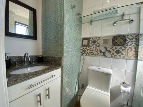 a bathroom with a toilet and a sink and a mirror at Ocean Flat 1006 in Vila Velha