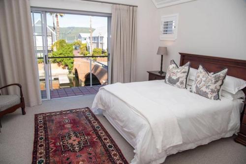 a bedroom with a white bed and a large window at Waterfront- C25 Knysna Quays with pool in Knysna