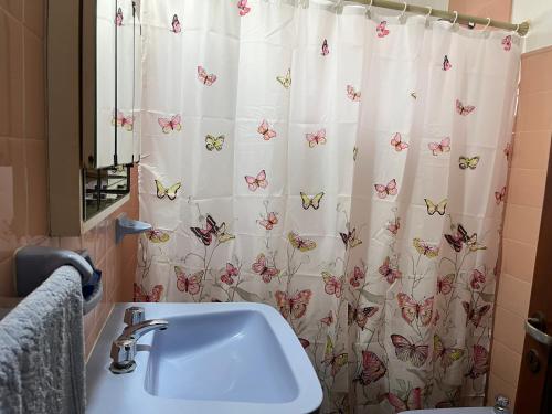 baño con lavabo y cortina de ducha con mariposas en Casa Rústica Norteña Candy Con Parking en Salta