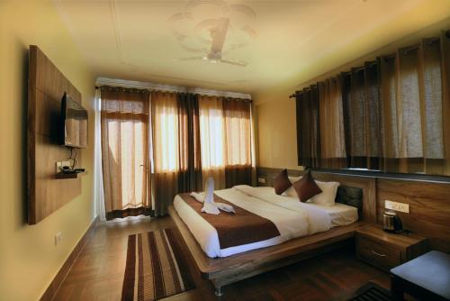 una camera con un grande letto e alcune finestre di Hotel Harmony Blue Mcleodganj, Dharamshala a Dharamshala