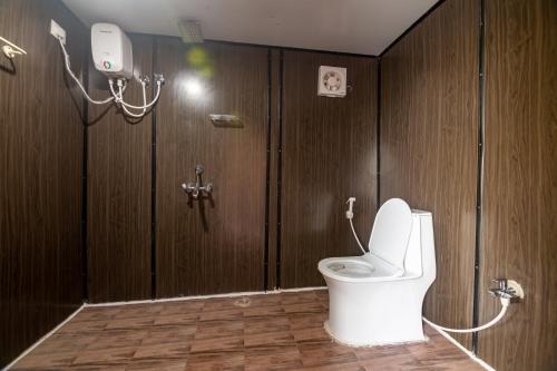 uma casa de banho com WC num quarto com paredes de madeira em Bliss Farm Stay- Tulip em Secunderābād