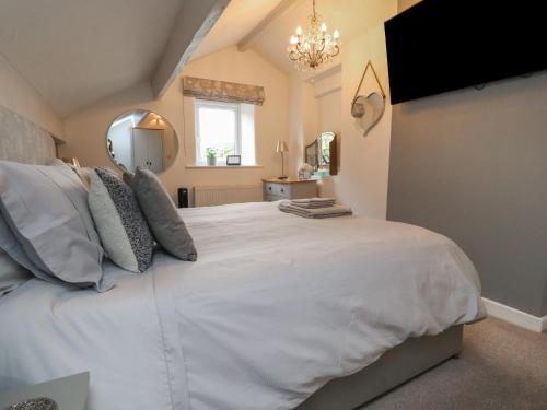 a bedroom with a large white bed and a mirror at Thimble Cottage in Keighley