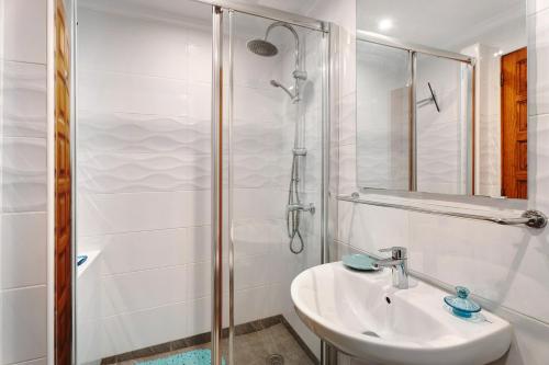 een witte badkamer met een wastafel en een douche bij Blue Dream Pebble Beach in San Miguel de Abona