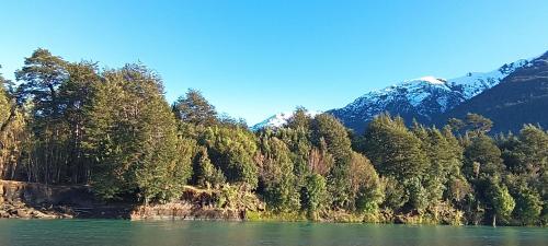 uitzicht op een rivier met bomen en bergen bij Cabaña La Rosa in Chaitén