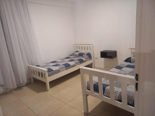 2 aparte bedden in een kleine kamer met gordijnen bij Apart272 in Río Cuarto