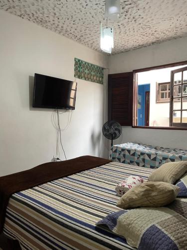 a bedroom with a bed and a flat screen tv at Suíte com cozinha para casal in Araruama