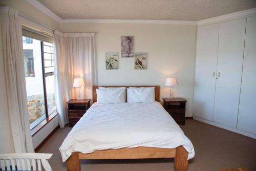 sypialnia z dużym łóżkiem z 2 stolikami nocnymi i oknem w obiekcie New Listing- 33 Laguna Grove on the water w mieście Knysna