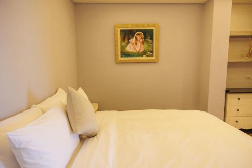 a bedroom with a white bed with a picture on the wall at Chill hill cottage in Taiping