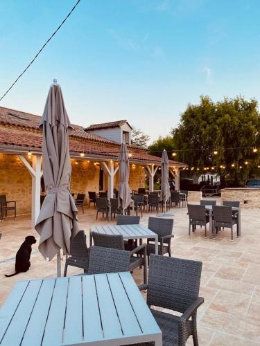 d'une terrasse avec des tables, des chaises et un parasol. dans l'établissement Parc St Vincent, à Lévignac-de-Guyenne