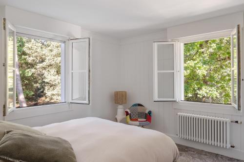 - une chambre blanche avec deux fenêtres et un lit dans l'établissement Villa Maison blanche, Arenal, à La Baule