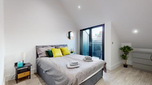ein Schlafzimmer mit einem Bett mit gelben Kissen und einem Fenster in der Unterkunft Penthouse Style Apartment in London