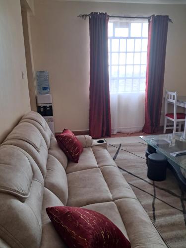 a living room with a large couch with red pillows at Tirisi Homes in Machakos
