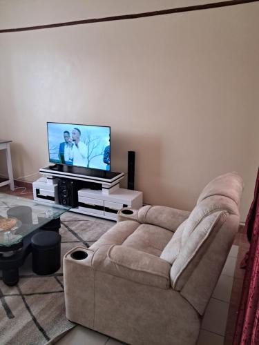 een woonkamer met een bank en een flatscreen-tv bij Tirisi Homes in Machakos