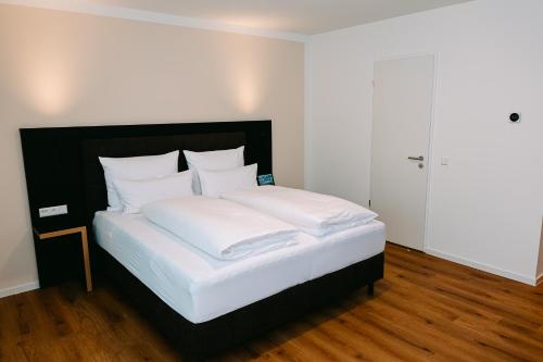 a bed with white sheets and pillows in a room at Hotel Restaurant Krone in Sulzbach am Kocher